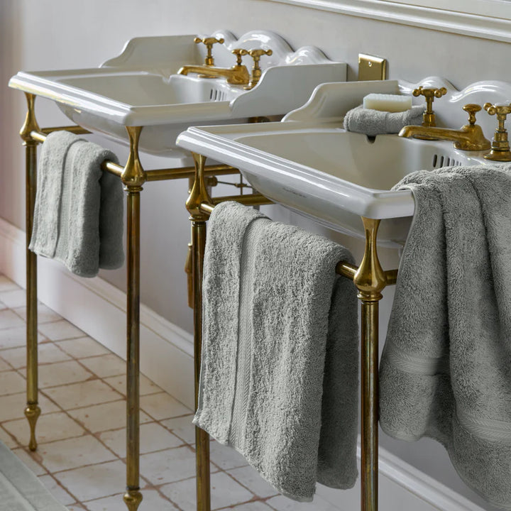 Bathroom vanity with white sinks, gold fixtures, and CHRISTY Renaissance Towels - Dove Grey.