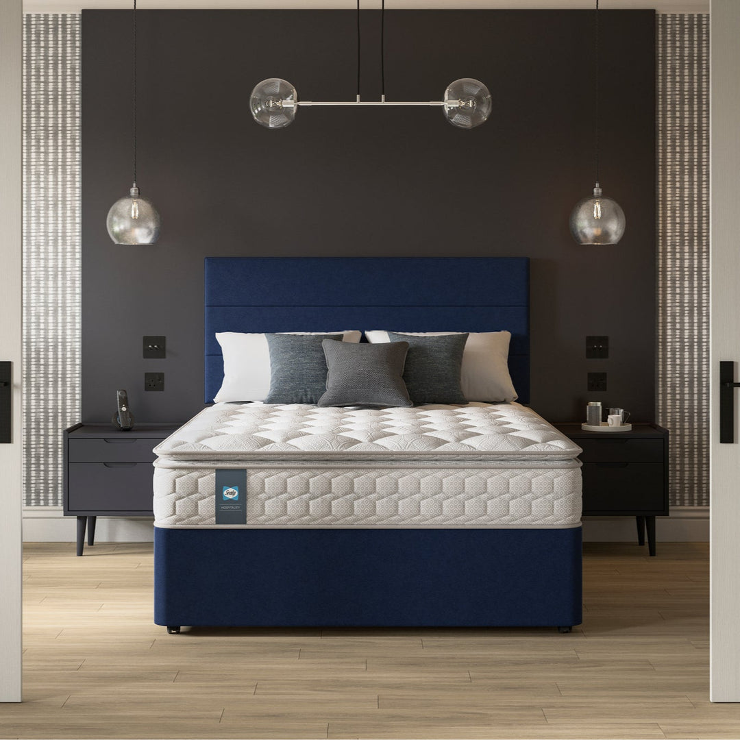 Bed with blue headboard and Sealy Sovereign hospitality mattress in a hotel bedroom setting
