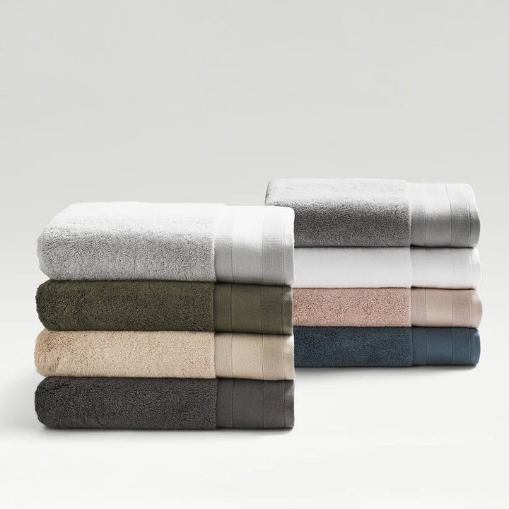 Stack of folded towels in various neutral colors on a light gray background