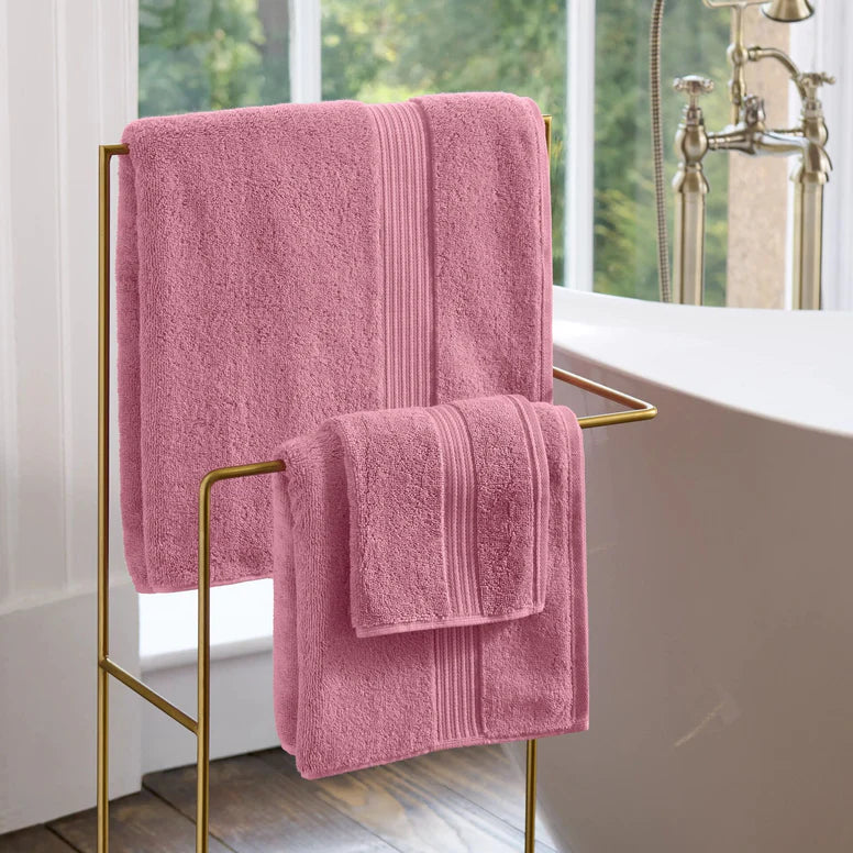 CHRISTY Supreme Hygro Towels - Blush hanging on a gold towel rack in a bathroom.