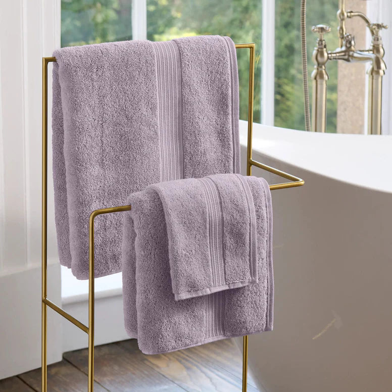 CHRISTY Supreme Hygro Towels - Lavender hanging on a gold towel rack in a bathroom.