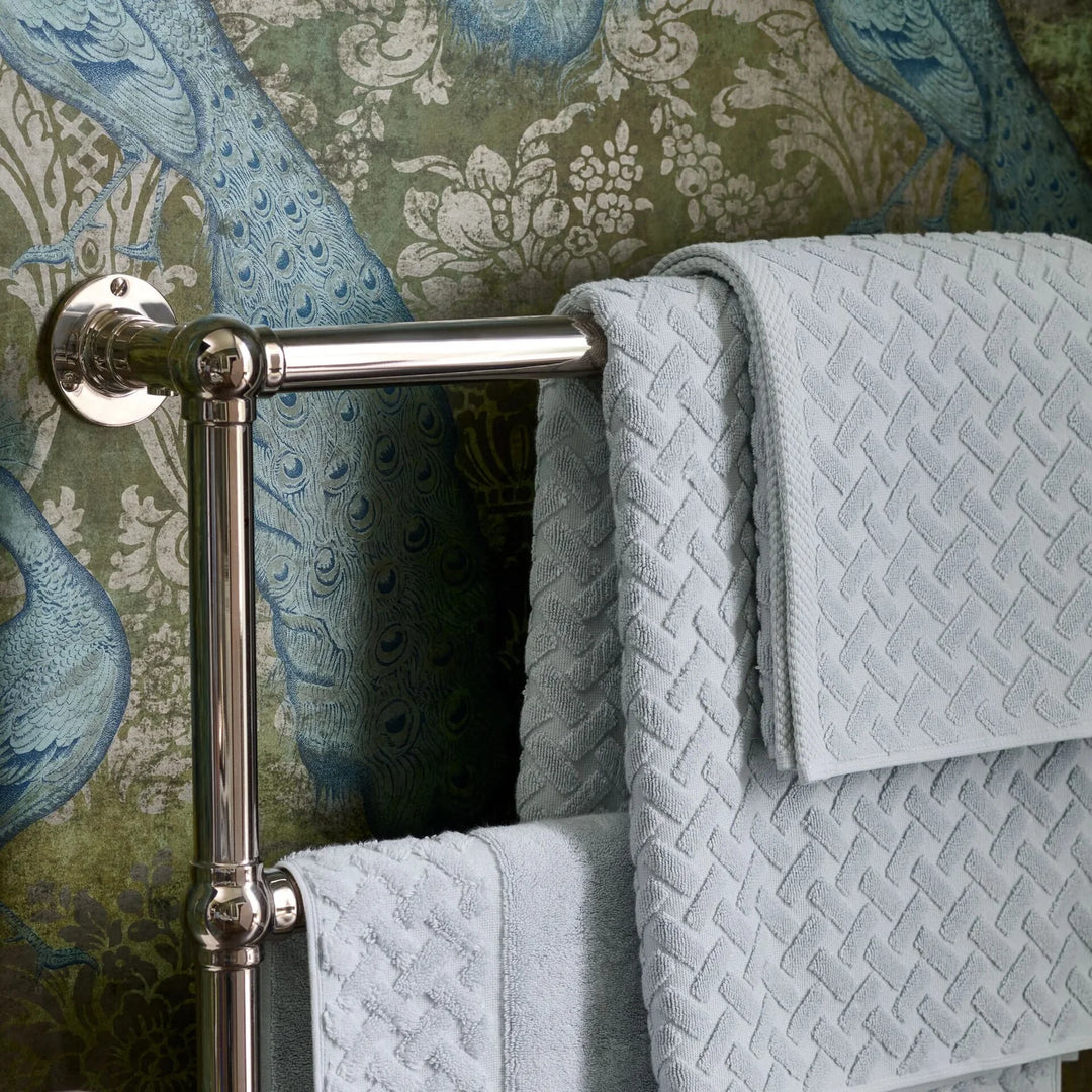 Towel rack with CHRISTY Trellis Towels - Glacier against a decorative wallpaper background