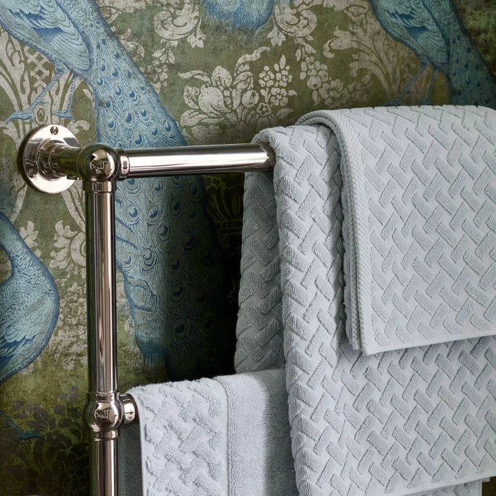 Towel rack with CHRISTY Trellis Towels - Glacier against a decorative wallpaper background