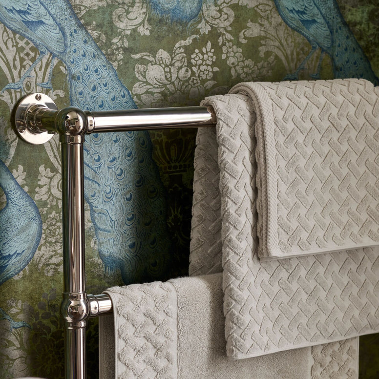 Towel rack with CHRISTY Trellis Towels - Oak against a decorative wall.