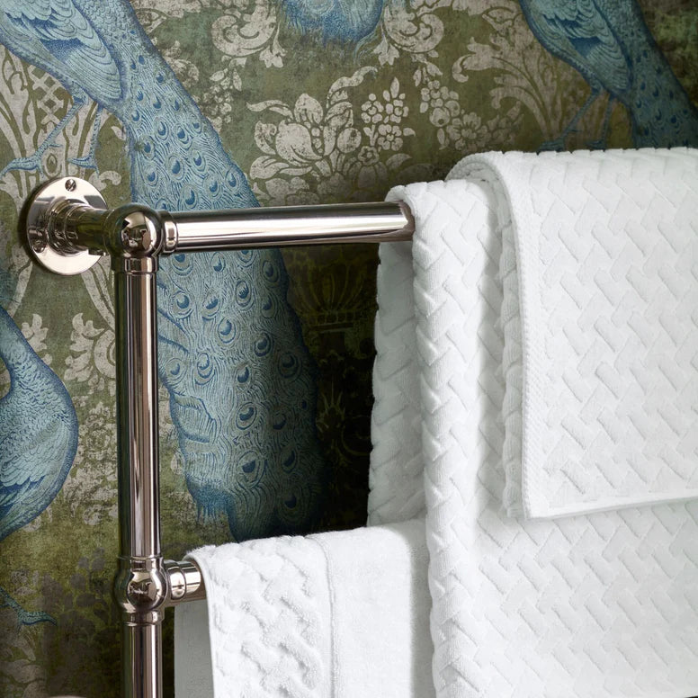 Towel rack with white towels against a decorative wallpaper background
