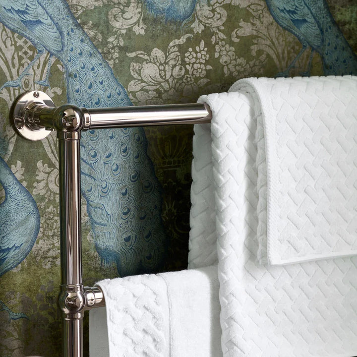Towel rack with white towels against a decorative wallpaper background