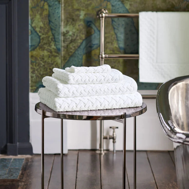 Stack of white towels on a round metal table with a decorative background