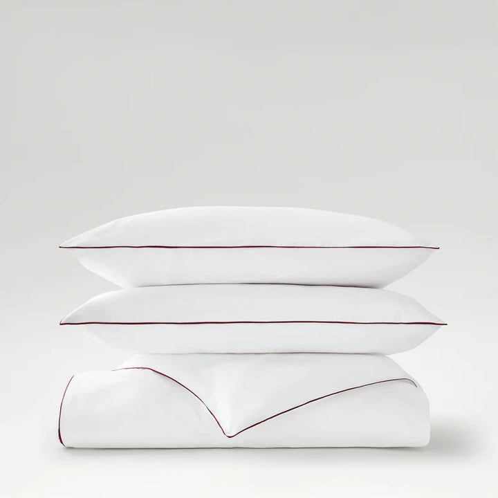 Two white pillows with red stitching on a light gray background