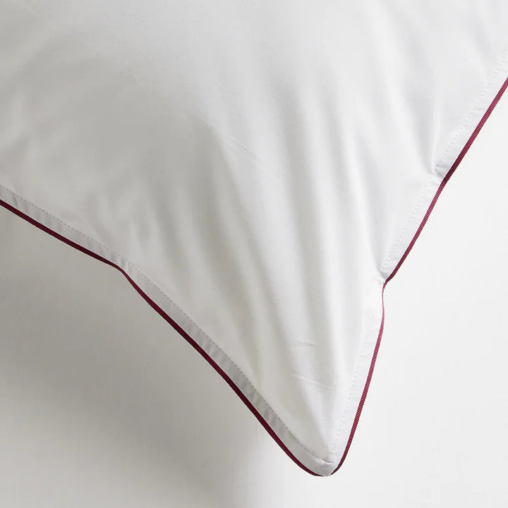 White pillow with red piping on a white background