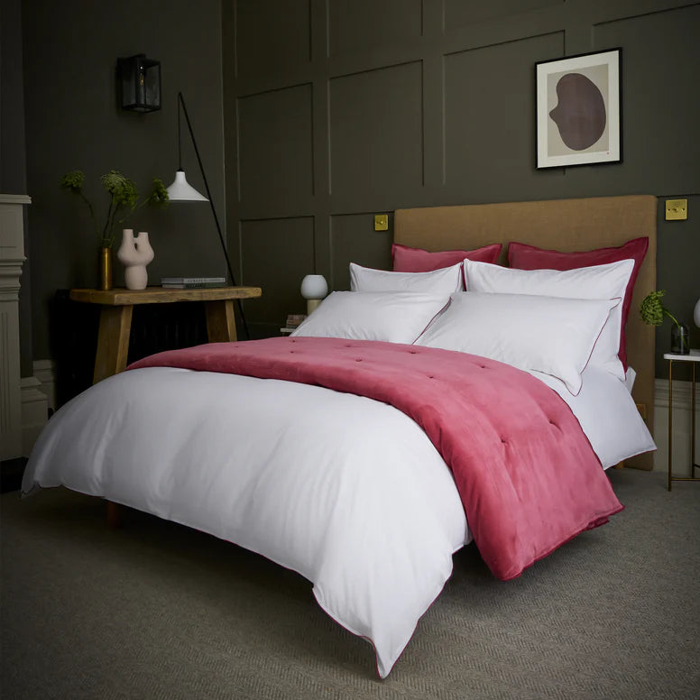 Bed with pink and white bedding in a dimly lit bedroom.